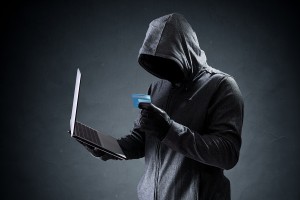 Computer hacker with credit card stealing data from a laptop concept for network security, identity theft and computer crime - Compliance3